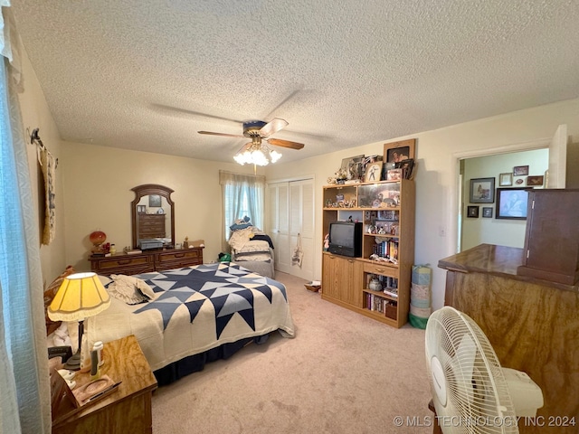 carpeted bedroom with a textured ceiling, a closet, and ceiling fan