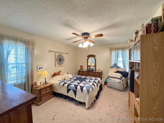 bedroom featuring multiple windows, ceiling fan, and light colored carpet