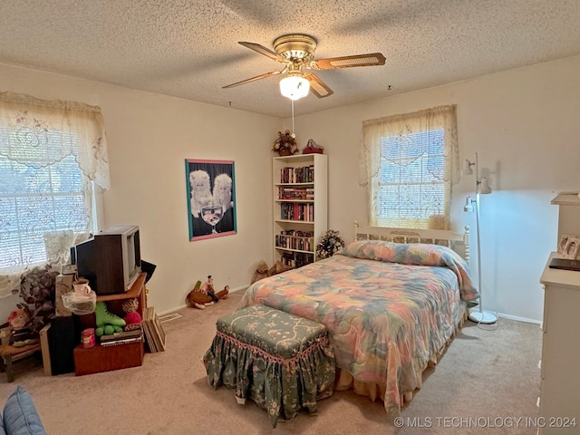 carpeted bedroom with ceiling fan and a textured ceiling