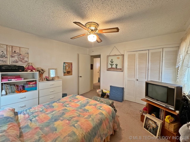 bedroom featuring ceiling fan, a closet, light carpet, and a textured ceiling