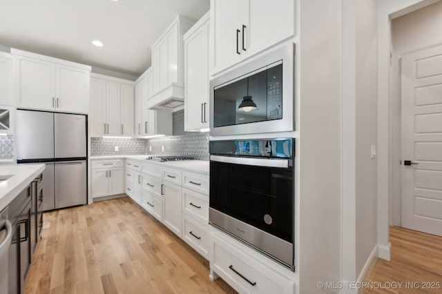 kitchen featuring hanging light fixtures, appliances with stainless steel finishes, white cabinetry, and backsplash