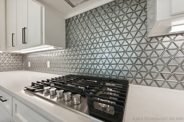 room details featuring backsplash, white cabinets, and stainless steel gas cooktop