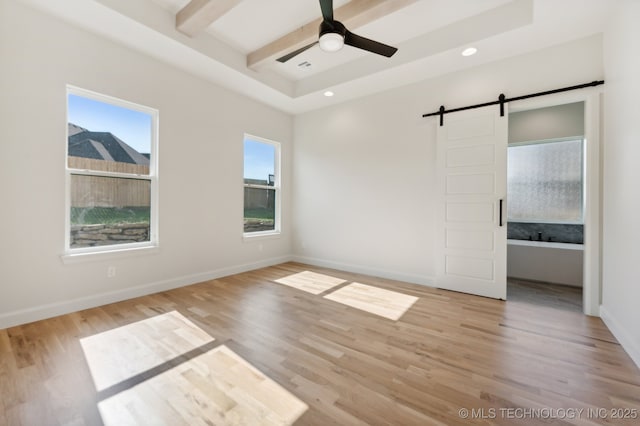 unfurnished bedroom with ceiling fan, beam ceiling, light hardwood / wood-style floors, and a barn door