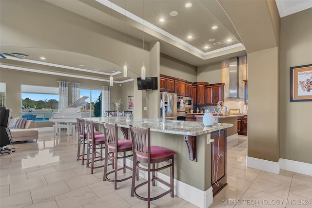 kitchen with a large island, stainless steel appliances, light stone counters, decorative backsplash, and a breakfast bar