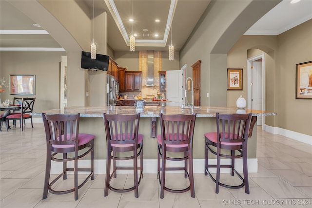 kitchen featuring stainless steel fridge, a kitchen breakfast bar, light stone counters, and a spacious island