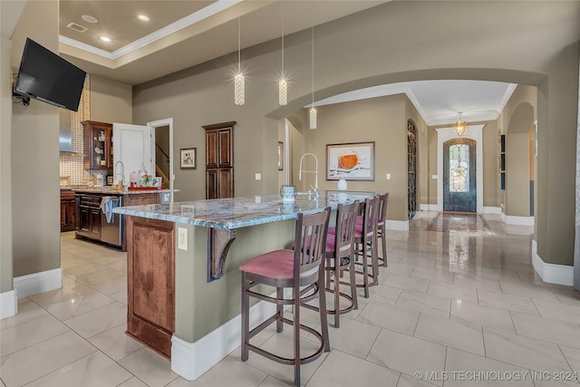 kitchen with a kitchen breakfast bar, backsplash, light stone counters, decorative light fixtures, and a large island