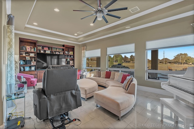 living room featuring ceiling fan, a raised ceiling, light tile patterned floors, and ornamental molding