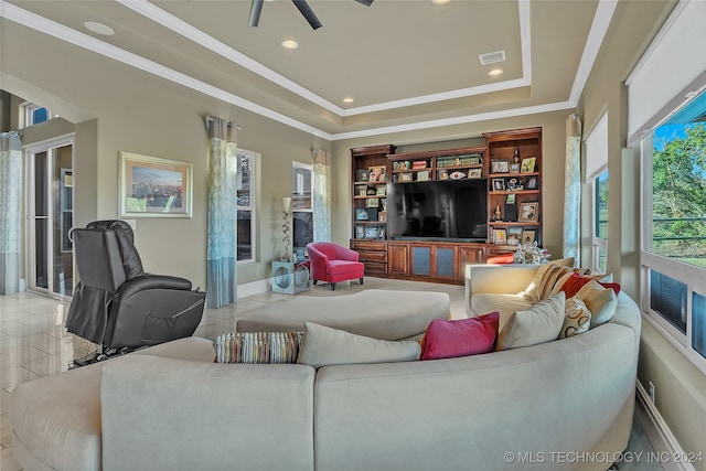 living room with a raised ceiling, ceiling fan, and ornamental molding