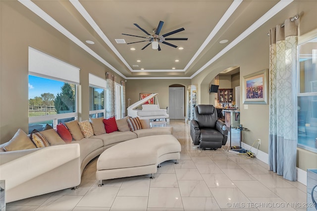 tiled living room featuring a raised ceiling and ceiling fan