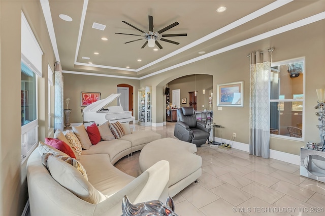 tiled living room featuring ceiling fan, a raised ceiling, and ornamental molding