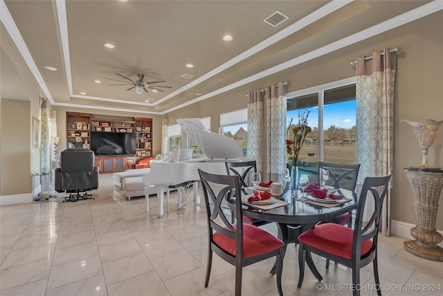 dining space with a raised ceiling, ceiling fan, ornamental molding, and light tile patterned flooring