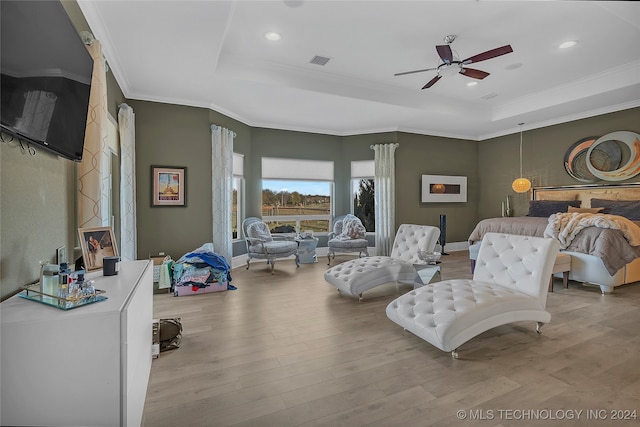 bedroom with a tray ceiling, ceiling fan, crown molding, and light wood-type flooring