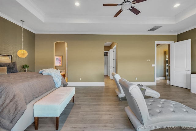 bedroom with a tray ceiling, ceiling fan, ornamental molding, and hardwood / wood-style flooring