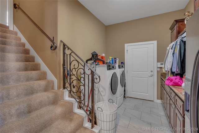 laundry room with washing machine and clothes dryer, light tile patterned flooring, and cabinets