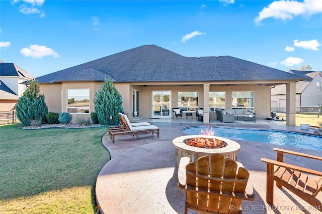 view of pool with a lawn, a patio area, ceiling fan, and an outdoor living space with a fire pit