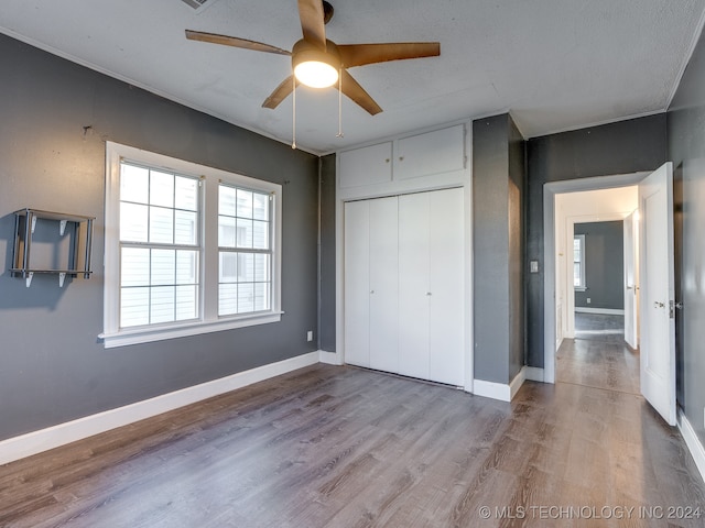 unfurnished bedroom featuring a textured ceiling, light wood-type flooring, a closet, and ceiling fan