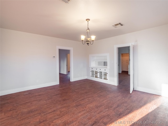 empty room featuring an inviting chandelier and dark wood-type flooring