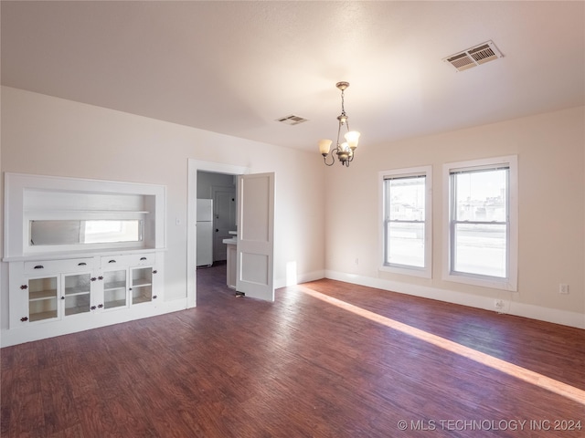 unfurnished living room featuring dark wood-type flooring and an inviting chandelier