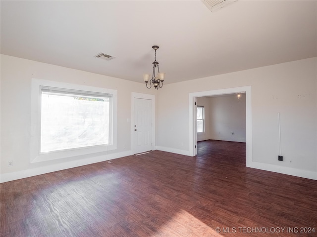 empty room featuring a chandelier, dark hardwood / wood-style floors, and a healthy amount of sunlight