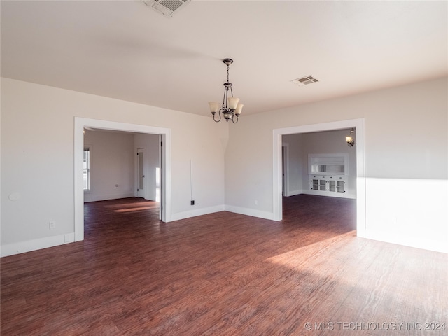 empty room with dark hardwood / wood-style flooring and a chandelier