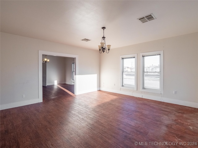 spare room featuring dark hardwood / wood-style flooring and a notable chandelier