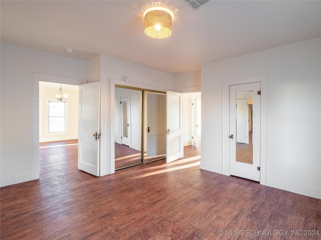 unfurnished bedroom with a closet, dark hardwood / wood-style flooring, and a chandelier