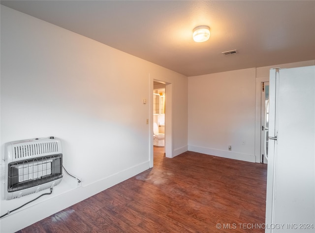 unfurnished room featuring heating unit and dark hardwood / wood-style floors