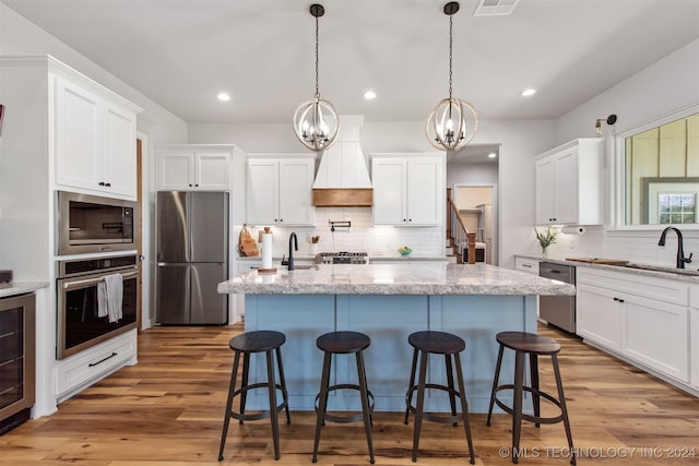 kitchen featuring white cabinets, light wood-type flooring, stainless steel appliances, and sink