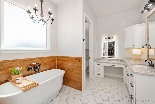 bathroom with toilet, vanity, a bath, and an inviting chandelier