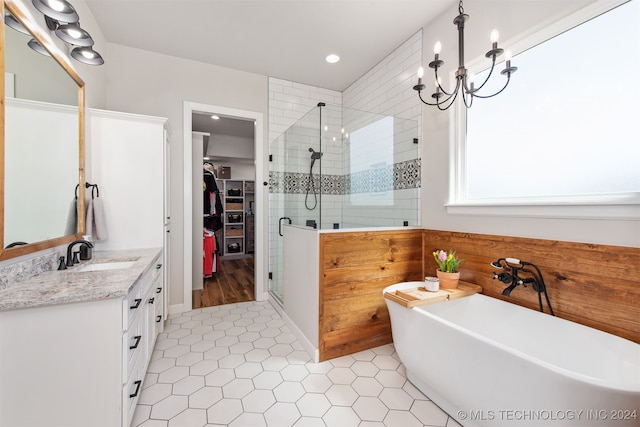 bathroom featuring plus walk in shower, vanity, an inviting chandelier, and tile patterned flooring