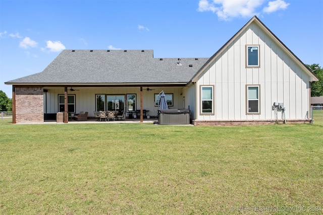 back of house featuring outdoor lounge area, ceiling fan, a patio, a hot tub, and a lawn