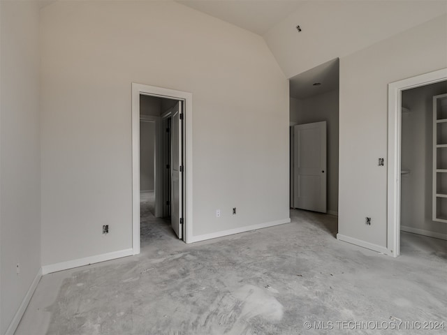 unfurnished bedroom with a walk in closet and lofted ceiling