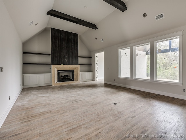 unfurnished living room with high vaulted ceiling, beamed ceiling, a healthy amount of sunlight, and light wood-type flooring