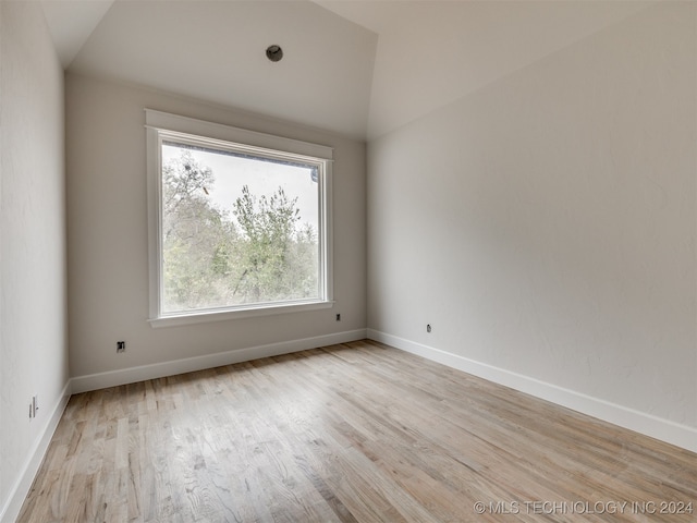 unfurnished room featuring light hardwood / wood-style flooring, vaulted ceiling, and a wealth of natural light