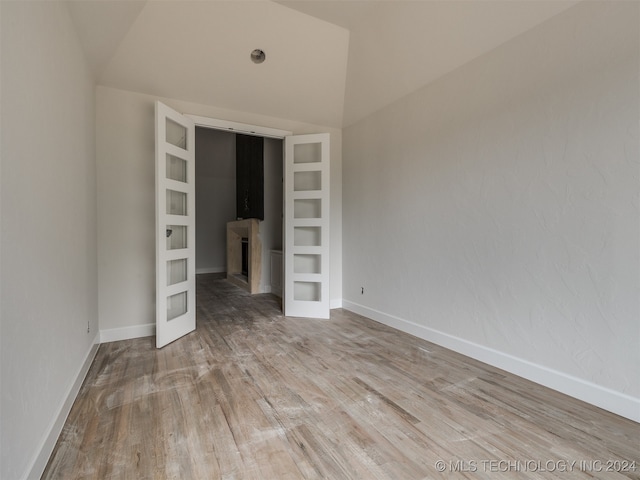 spare room featuring lofted ceiling, light hardwood / wood-style floors, and built in features