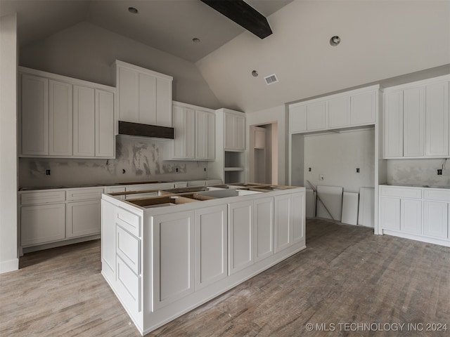 kitchen featuring light wood-type flooring, a center island, tasteful backsplash, and white cabinetry