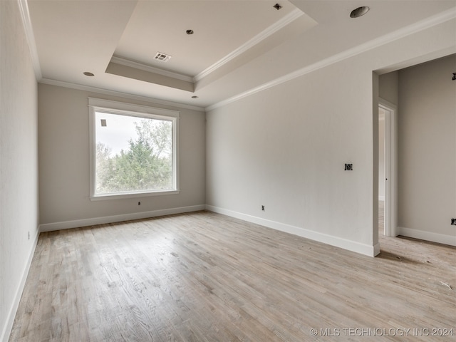 unfurnished room featuring light hardwood / wood-style floors, a tray ceiling, and ornamental molding