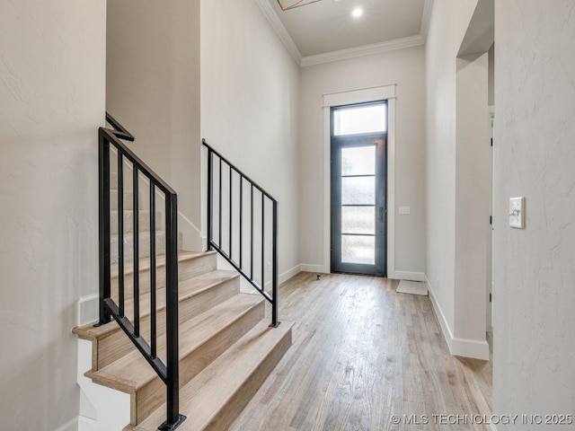 foyer entrance with ornamental molding and light hardwood / wood-style floors