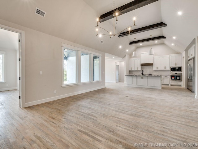 unfurnished living room featuring plenty of natural light, sink, a notable chandelier, and light hardwood / wood-style floors