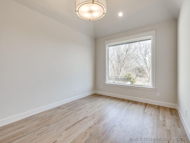 unfurnished room with vaulted ceiling and light wood-type flooring