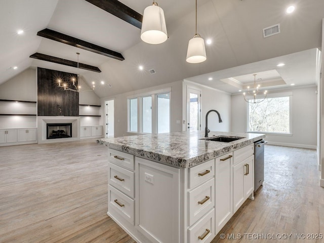 kitchen featuring hanging light fixtures, sink, and a center island with sink