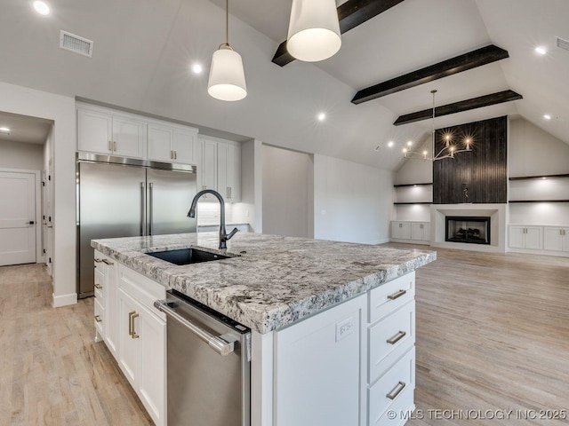 kitchen with sink, white cabinetry, stainless steel appliances, a center island with sink, and decorative light fixtures