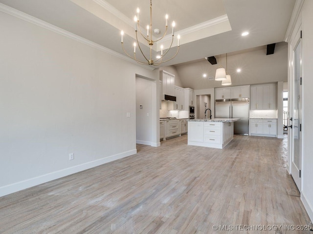 kitchen featuring sink, decorative light fixtures, a kitchen island with sink, stainless steel appliances, and light hardwood / wood-style floors