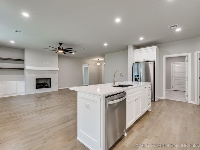 kitchen with a sink, ceiling fan, stainless steel appliances, white cabinets, and visible vents