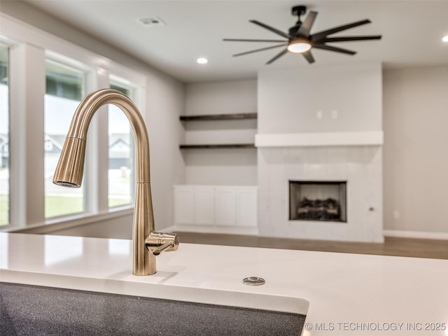 details with open shelves, a tile fireplace, a sink, and recessed lighting