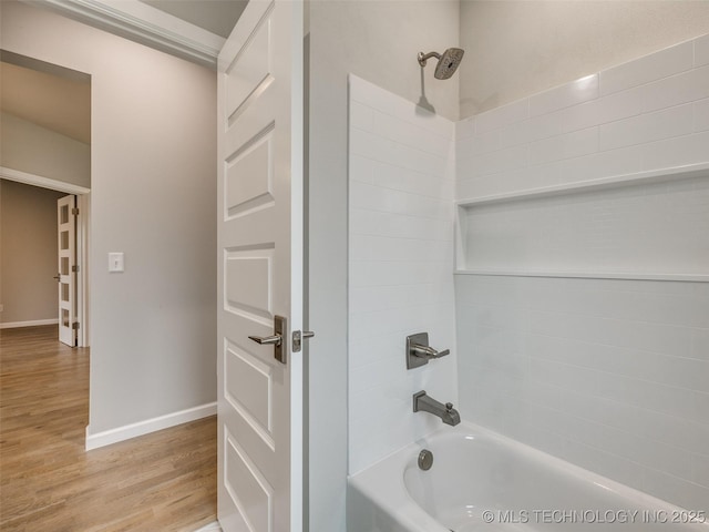 full bath with baseboards, wood finished floors, and washtub / shower combination