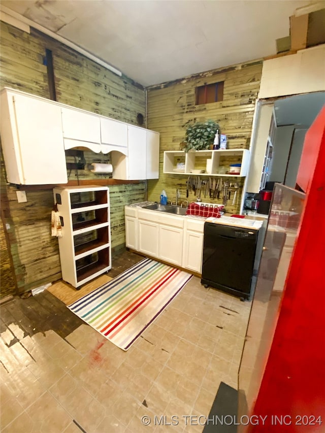 kitchen featuring white cabinets, sink, and wooden walls