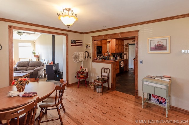 dining space with crown molding, ceiling fan, and light wood-type flooring