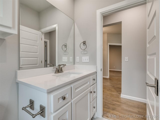 bathroom featuring baseboards, wood finished floors, and vanity