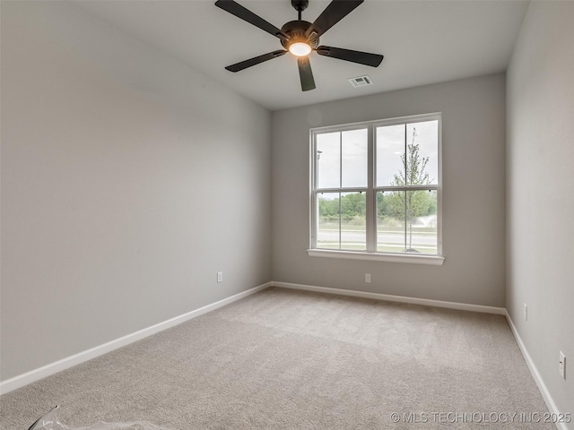 carpeted spare room with visible vents, baseboards, and ceiling fan
